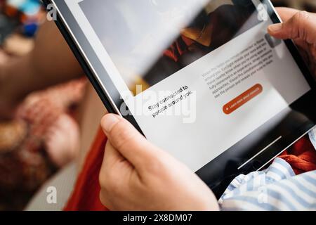 London, Großbritannien - 11. Juni 2023: Eine neugierige Frau liest in einem gemütlichen Wohnzimmer über das VisionOS des Apple Vision Pro Mixed-Reality-Headsets auf ihrem iPad Pro Stockfoto