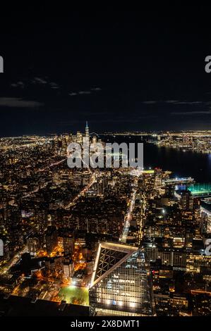 Manhattans nächtliche Skyline aus einer gewagten Perspektive von oben. Hoch aufragende Riesen durchdringen die Wolken und bieten einen einzigartigen Aussichtspunkt für Reisen. Stockfoto