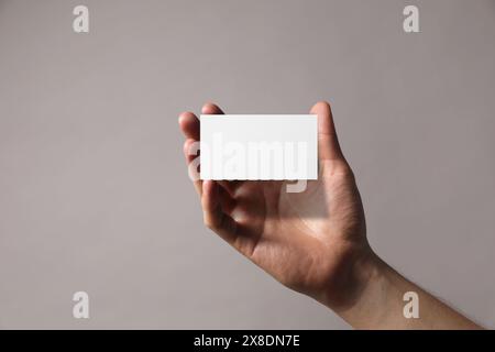 Mann mit leerer Visitenkarte auf grauem Hintergrund, Nahaufnahme. Modell für Design Stockfoto