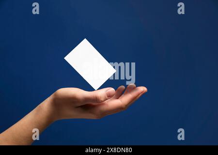 Frau mit leerer Visitenkarte auf blauem Hintergrund, Nahaufnahme. Modell für Design Stockfoto