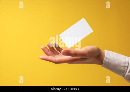 Frau mit leerer Visitenkarte auf gelbem Hintergrund, Nahaufnahme. Modell für Design Stockfoto