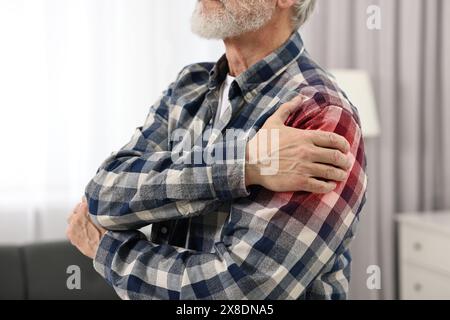 Ein älterer Mann leidet an Schmerzen in der Schulter drinnen, Nahaufnahme Stockfoto