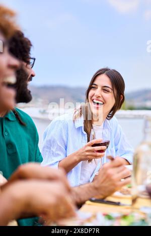 Eine Gruppe junger, fröhlicher Millennial-Freunde, die lachten, versammelte sich auf einer Grillparty im Freien. Stockfoto