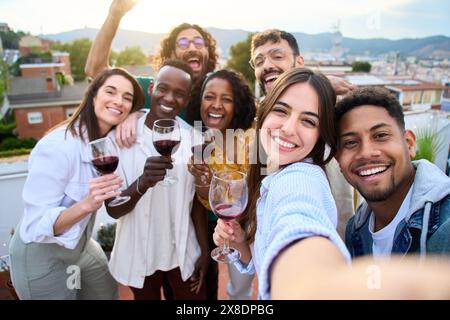Gruppe mit verschiedenen Freunden, die Spaß auf der Dachparty haben. Schöne Frau, die Selfie beim Barbecue macht. Stockfoto