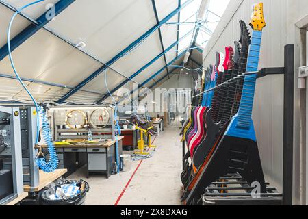 Prozess der Erstellung wunderschöner E-Gitarren mit komplizierten Details und Saiten, perfekt für die Herstellung einzigartiger Musik, Kohlefaserformmaschinen im Hintergrund. Hochwertige Fotos Stockfoto