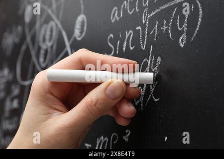 Der Lehrer schreibt mathematische Formeln mit Kreide auf der Tafel, Nahaufnahme Stockfoto