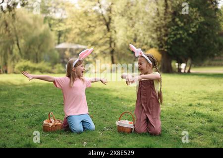 Osterfeier. Süße kleine Mädchen in Hasenohren mit Korbkörben draußen Stockfoto