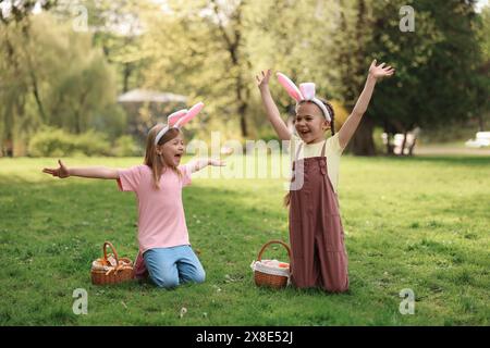 Osterfeier. Süße kleine Mädchen in Hasenohren mit Korbkörben draußen Stockfoto