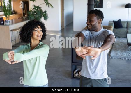 Ein vielseitiges Paar, das zu Hause in legeren Kleidern tanzt Stockfoto