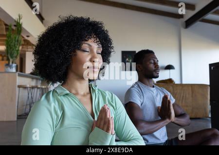 Ein vielseitiges Paar zu Hause, das zusammen Yoga praktiziert Stockfoto