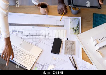 Gruppe verschiedener Kollegen, die am Tisch an Architekturzeichnungen arbeiten Stockfoto