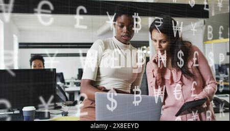 Bild von Währungssymbolen gegen zwei verschiedene Frauen, die im Amt diskutieren Stockfoto