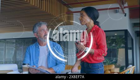 Eine Gruppe von Führungskräften bespricht etwas auf einem Schreibtisch in einem Büro Stockfoto