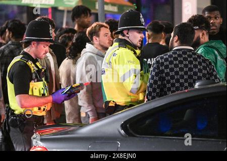 Broad Street, Birmingham, 25. Mai 2024 - die Polizei sprach mit Männern hier, die mit der Klasse-C-Droge Lachgas gesichtet wurden. Revellers gingen am Freitagabend in die berüchtigte Broad Street von Birmingham, um die Feiertagsfeier zu beginnen. Die Partygäste haben Rosies und Heidis Nachtklubs in den Streifen gepackt. Gruppen von Freunden posierten für Fotos, während andere ihren Freunden Huckepacks die Straße hinunter von Club zu Club gaben. Die West Midlands Police war ebenfalls außer Kraft. Eine Gruppe von Männern wurde von zwei Polizisten befragt, nachdem sie mit einem großen Kanister mit Lachgas, auch bekannt als „Hippie Crack“, entdeckt wurden Stockfoto