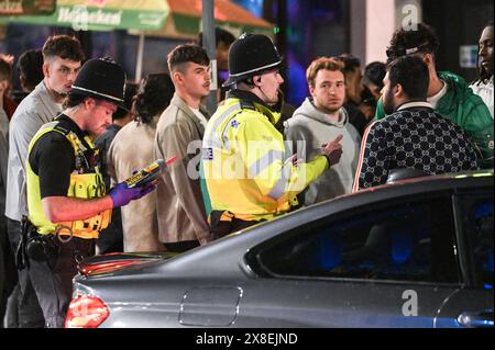 Broad Street, Birmingham, 25. Mai 2024 - die Polizei sprach mit Männern hier, die mit der Klasse-C-Droge Lachgas gesichtet wurden. Revellers gingen am Freitagabend in die berüchtigte Broad Street von Birmingham, um die Feiertagsfeier zu beginnen. Die Partygäste haben Rosies und Heidis Nachtklubs in den Streifen gepackt. Gruppen von Freunden posierten für Fotos, während andere ihren Freunden Huckepacks die Straße hinunter von Club zu Club gaben. Die West Midlands Police war ebenfalls außer Kraft. Eine Gruppe von Männern wurde von zwei Polizisten befragt, nachdem sie mit einem großen Kanister mit Lachgas, auch bekannt als „Hippie Crack“, entdeckt wurden Stockfoto