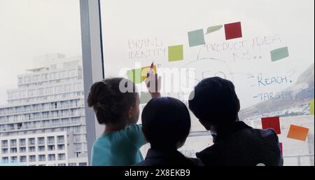 Drei kleine Kinder, zwei rassische und ein Kaukasier, arbeiten am Projekt zusammen Stockfoto