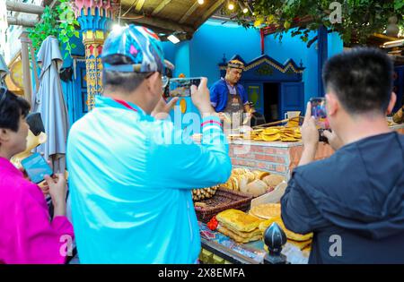 URUMQI, CHINA - 24. MAI 2024 - Touristen beobachten die Herstellung von Naan-Brot auf dem Xinjiang International Grand Bazaar in Urumqi, Provinz Xinjiang, China Stockfoto