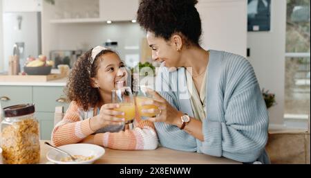 Küche, Mutter und Mädchen mit Lächeln, Saft und Jubel zum Frühstück, Binden und Liebe im Haus. Zuhause, Mutter und Tochter in der Wohnung, glücklich und fürsorglich Stockfoto