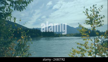 Bäume um den ruhigen Fluss herum, mit einem Berg in der Ferne Stockfoto