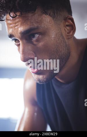 Ein starker und fitter birassischer Mann arbeitet intensiv im Fitnessstudio. Schweiß schimmert auf seinem Gesicht, während er sich auf seine Trainingsroutine im hell beleuchteten Fitnessstudio konzentriert Stockfoto