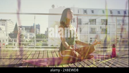 Bild von Pflanzen über birassische Frau, die Yoga praktiziert Stockfoto