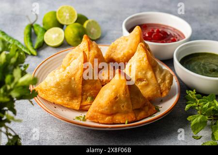 Selective Focus Samosa, mit Kartoffeln gefülltes Gebäck, knusprige, herzhafte, beliebte indische Snacks mit Tomaten- und Minzchutney-Tees. Stockfoto