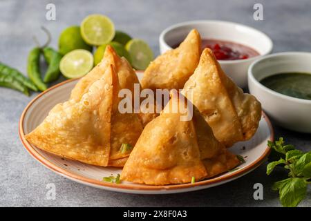 Selective Focus Samosa, mit Kartoffeln gefülltes Gebäck, knusprige, herzhafte, beliebte indische Snacks mit Tomaten- und Minzchutney-Tees. Stockfoto