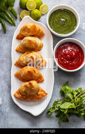 Selective Focus Samosa, mit Kartoffeln gefülltes Gebäck, knusprige, herzhafte, beliebte indische Snacks mit Tomaten- und Minzchutney-Tees. Stockfoto