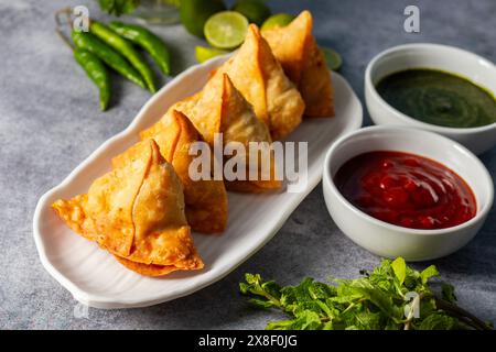 Selective Focus Samosa, mit Kartoffeln gefülltes Gebäck, knusprige, herzhafte, beliebte indische Snacks mit Tomaten- und Minzchutney-Tees. Stockfoto