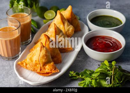 Selective Focus Samosa, mit Kartoffeln gefülltes Gebäck, knusprige, herzhafte, beliebte indische Snacks mit Tomaten- und Minzchutney-Tees. Stockfoto