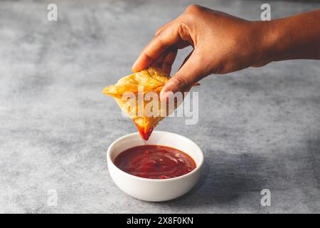 Eine Dame, die Samosa in Tomatensauce taucht. Indisches Street Food. Stockfoto