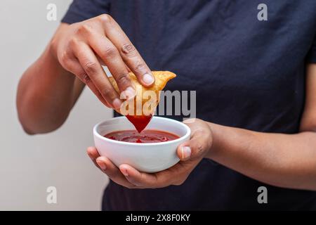 Eine Dame, die Samosa in Tomatensauce taucht. Indisches Street Food. Stockfoto