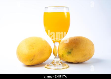Frischer Mangosaft in einem Glas mit Mangobrüchten auf weißem Hintergrund. Sommergetränk. Stockfoto