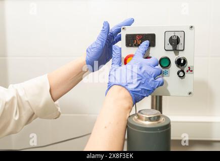 Hände in blauen Handschuhen in der Produktion den Betriebsmodus der Ausrüstung durch Drücken der Tasten und des Bildschirms einstellen. Hochwertige Fotos Stockfoto