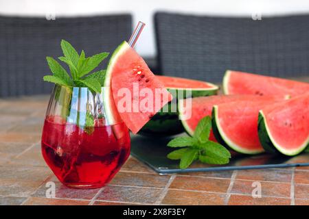 Roter Eiscocktail oder kaltes Wassermelonengetränk mit Minzblättern, erfrischendes Sommergetränk mit geschnittenen Wassermelonen Stockfoto