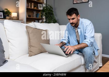 Junge gestresste freiberufliche Männer, die zu Hause arbeiten, haben Probleme mit dem Laptop. Malware oder Computerfehler machen ihm während seiner Arbeit Sorgen. Nervöser Geschäftsmann Stockfoto