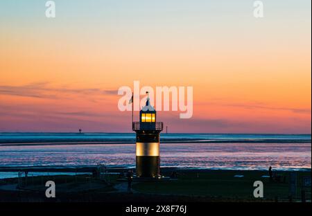 Schwarz-weißer Leuchtturm, genannt „kleine Preusse“, Leuchtturm und Boot bei Sonnenuntergang an der Küste, Himmel in warmen Farben, Himmel ändert sich von blau zu Stockfoto