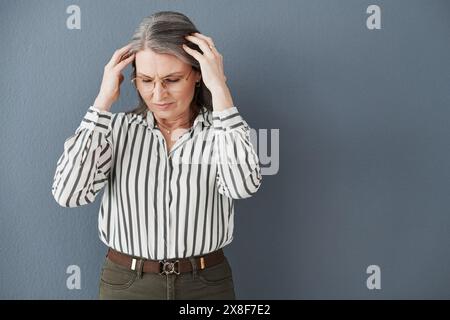 Reife, Frau und Kopfschmerzen von der Arbeit Stress, Angst oder Gehirnnebel für die psychische Gesundheit im Studio. Verärgerte und leitende Person oder ceo mit Hand an Kopf von Stockfoto