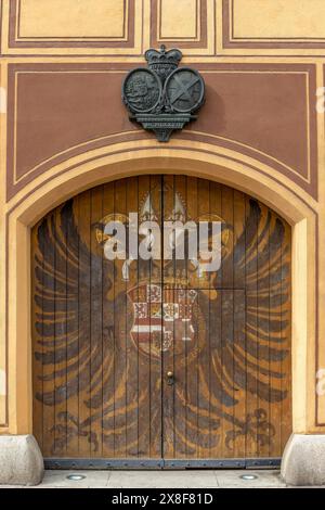 Ein massiver Tortor mit einem großen Bild eines Doppeladlers und einem Wappen darüber am Fuggerhaeuser in der Maximilianstraße in Augsburg Stockfoto