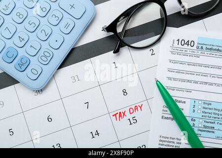 Steuertag. Kalender mit Datumserinnerung, Dokument, Stift, Brille und Taschenrechner auf Tisch, flach gelegt Stockfoto