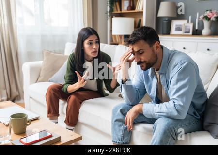 Kommunikationsprobleme, Beziehungsschwierigkeiten. Junge Paare, Mann und Frau, die zu Hause auf dem Sofa sitzen, streiten und missverstehen. Zwei wütende und traurige p Stockfoto