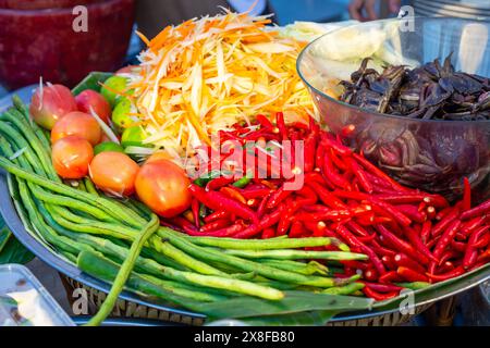 Street Food in Asien. Zutaten für die Zubereitung von Som Tam-Salat. Geschnittenes Gemüse und Gewürze auf einem Teller. Stockfoto