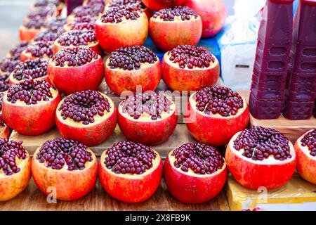 Granatapfel mit der Oberseite abschneiden die Früchte und saftigen Samen an einem Marktstand. Zubereitung von Granatapfelsaft. Stockfoto