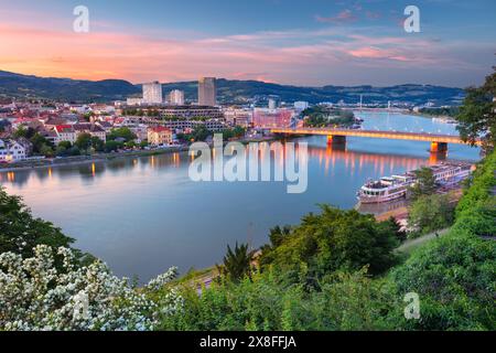 Linz, Österreich. Luftbild des Flusses Linz, Österreich während des Frühlingsuntergangs mit Reflexion der Stadtlichter in der Donau. Stockfoto