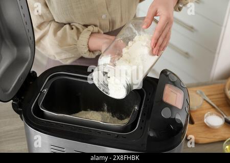 Teig herstellen. Frau, die Mehl in die Brotbackmaschine am Tisch gab, Nahaufnahme Stockfoto