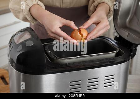 Teig herstellen. Frau, die Ei in die Brotbackpfanne bricht, Nahaufnahme Stockfoto