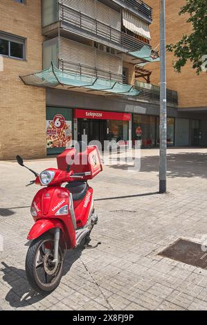 Viladecans, Barcelona, Spanien-25. Mai 2024: Roter Telepizza-Roller mit Lieferbox auf einem Gehweg vor einem Telepizza-Geschäft. Fastfood del Stockfoto