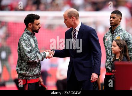 Der Prince of Wales schüttelt sich vor dem Finale des Emirates FA Cup im Wembley Stadium, London, mit Bruno Fernandes von Manchester United (links) die Hand. Bilddatum: Samstag, 25. Mai 2024. Stockfoto