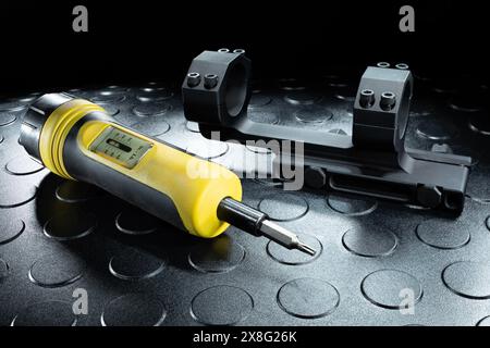 Torgue-Werkzeug, das in Pfund misst, neben einem Gewehrsockel mit acht Schrauben, um die Optik sicher auf der Pistole zu halten. Stockfoto