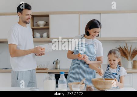 Eine Familienkochzeit mit einem Vater, der hilft, während Mutter und Tochter einen Teig mischen. Stockfoto